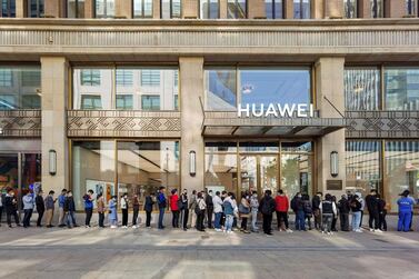 People wearing masks wait in line in front of the Huawei’s flagship store for pre-sales of the newly launched Huawei Mate 40 series smartphones in Shanghai. AFP