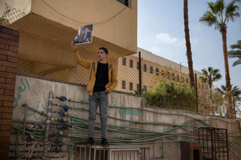 A supporter of former President Hosni Mubarak holds a poster with his photograph near the cemetery where he will be buried. AP Photo