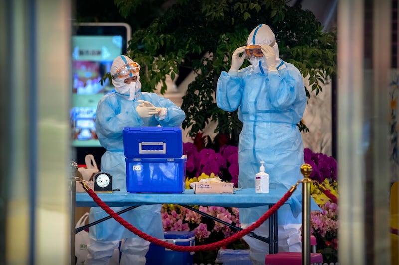 Workers put on protective suits before giving Covid-19 tests to foreign journalists covering a press conference for China's National People's Conference at a hotel in Beijing. AP Photo