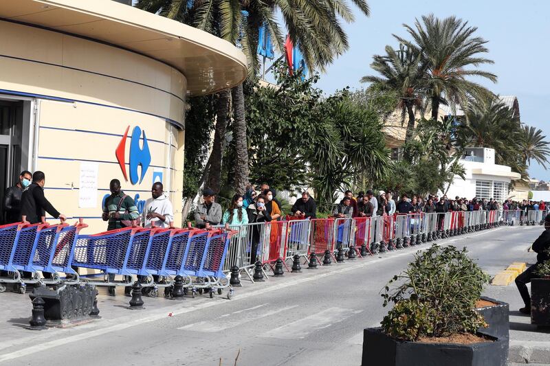 Customers wearing protective face masks queue outside a supermarket in Tunis, Tunisia.  EPA