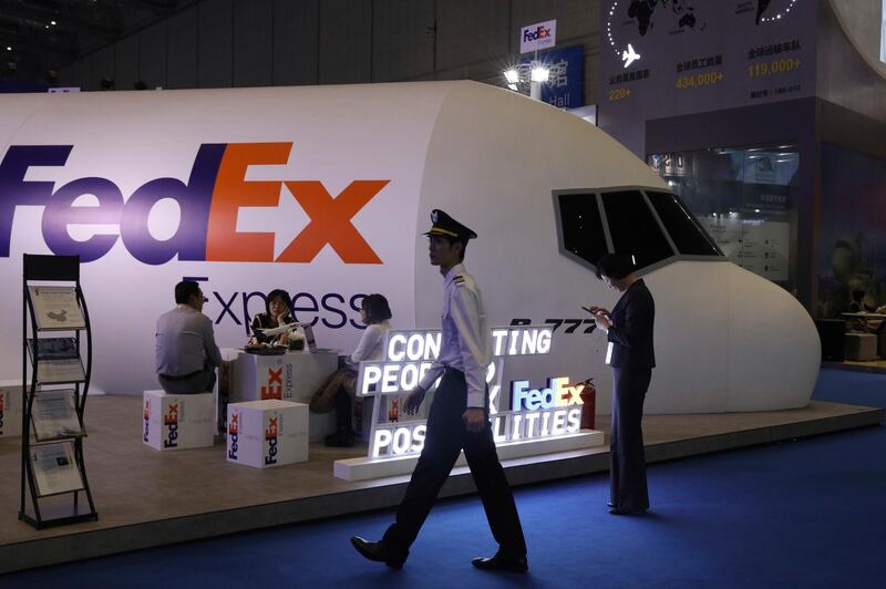 FILE - In this Nov. 5, 2018, file photo, a man dressed as a pilot walks past the FedEx booth during the China International Import Expo in Shanghai. China's state media said Saturday, June 1, 2019, that the country is investigating FedEx after it diverted packages sent by Chinese tech giant Huawei. (AP Photo/Ng Han Guan, File)