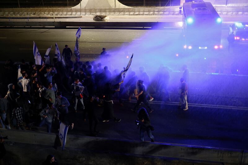 Protesters are sprayed with a water cannon as they block a road during a demonstration, in Tel Aviv. Reuters