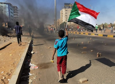 A young boy waves Sudan's flag as protesters block a street in the Sudanese capital Khartoum during antimilitary demonstrations. AFP