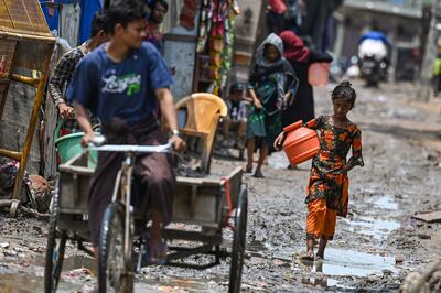 A Rohingya refugee girl walks through a muddy street at a refugee camp in New Delhi in June, 2023. AFP