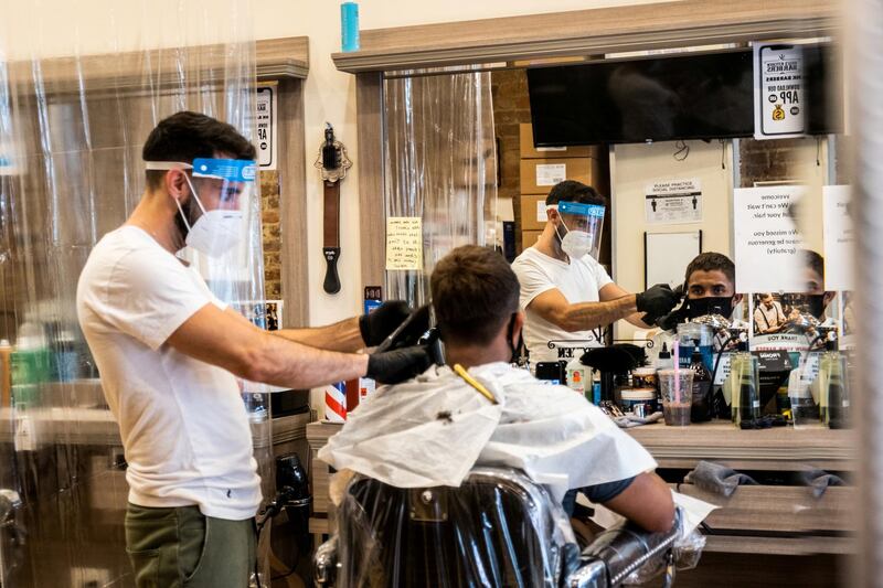 A customer wearing a face mask gets a haircut at a barber shop in New York City. Reuters