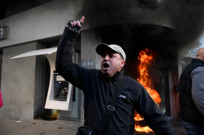 A man shouts slogans as tyres burn outside an Audi Bank branch during a protest by depositors on February 16, 2023. EPA