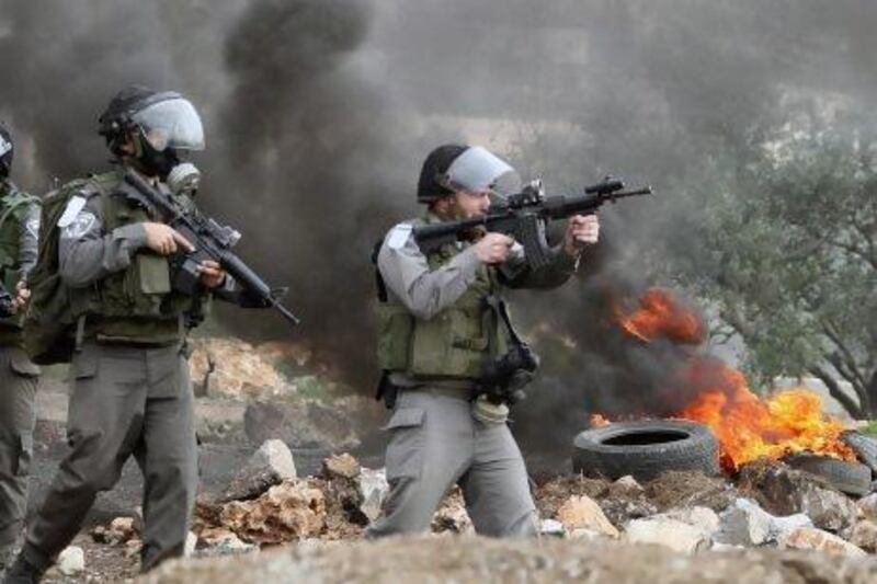 Israeli soldiers wearing gas masks point towards Palestinians during a protest against the annexation of Palestinian land in the village of Kafr Qadum, near Nablus, in the occupied West Bank.