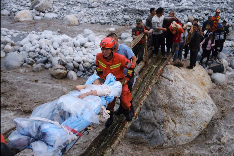 Rescuers carry survivors across a makeshift bridge after an earthquake shook China's south-western province of Sichuan on Monday. AP