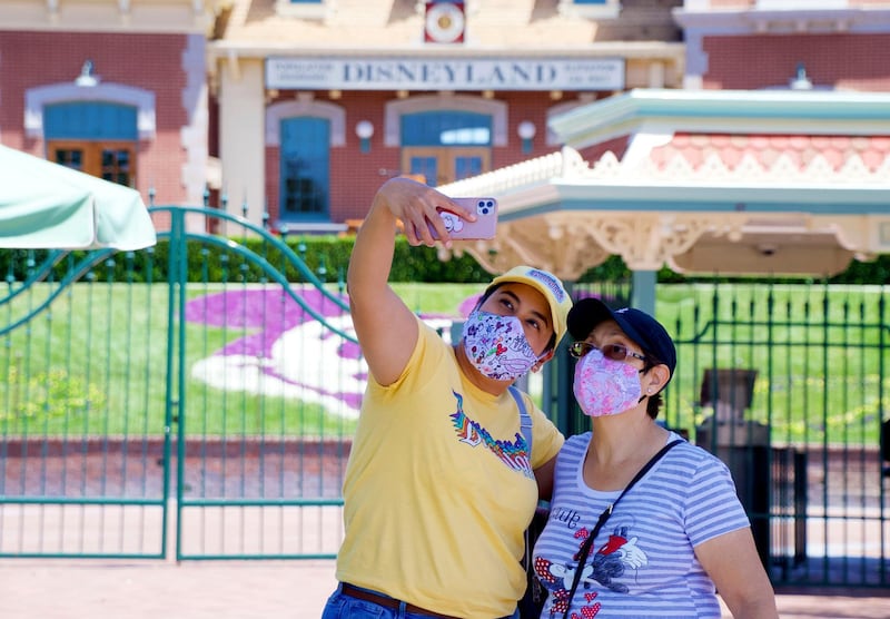 Maria Delgadillo takes a selfie with her mother Rosa Torres at the entrance to Disneyland on the reopening day of the Downtown Disney District on its reopening day in Anaheim, Calif.  AP