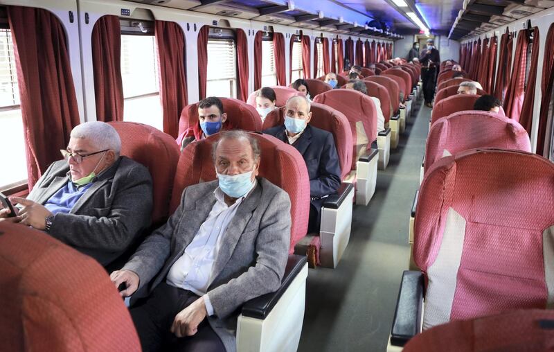 epa08919822 People wearing face masks sit aboard a train, at the main train station, in Cairo, Egypt, 05 January 2021. The Egyptian government imposed a fine of 50 EGP (2.60 euro) from 03 January, to any individual not wearing a face mask when entering or working in markets, businesses, government installations, private establishments and banks, and also while riding in public or private mass transportation. This move is to help stop the spread of the coronavirus during the second wave of the pandemic.  EPA/KHALED ELFIQI