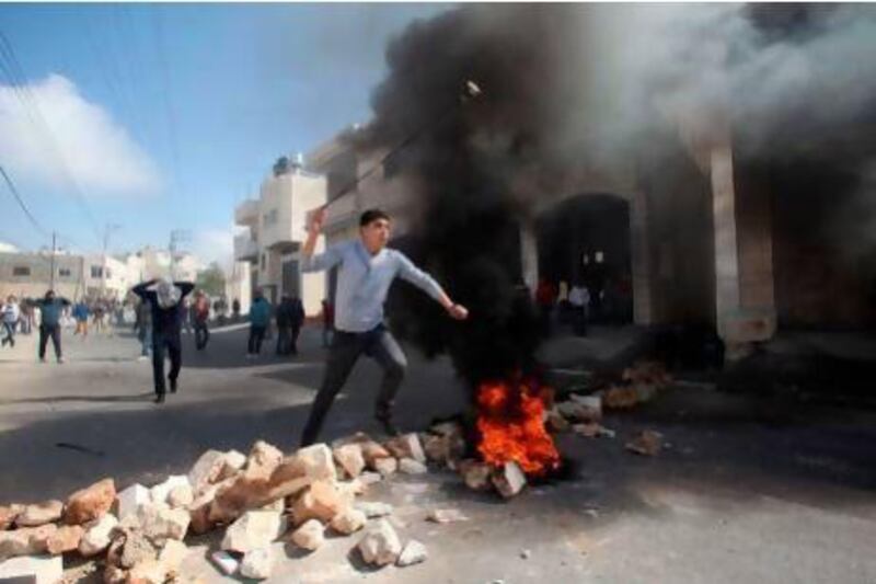 A Palestinian protester hurl stones at Israeli security forces during clashes in the village of Saair in the West Bank on Friday, following the death of a Palestinian prisoner held in Israel. Hazem Bader / AFP