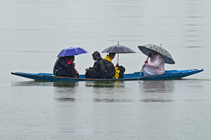 Travellers cross the Dal Lake in Srinagar, India, during rainfall.  AFP