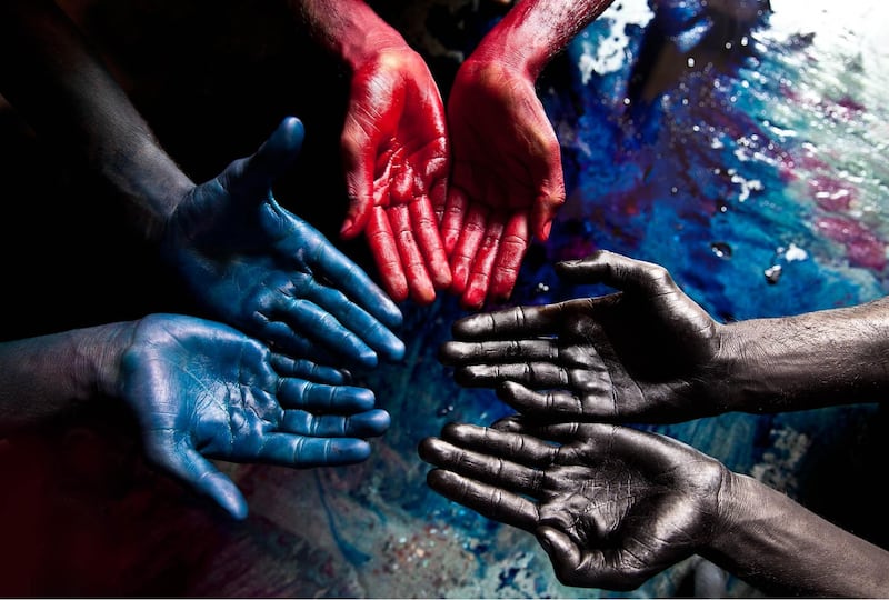 In 'Family Portrait', Kristine depicts how slavery can last through generations. The dyed black hands are of the father's, and the blue red and hands are his sons's. Using their bare hands, these silk dyers in an Indian village dip the cloth in barrels filled with toxic dye.