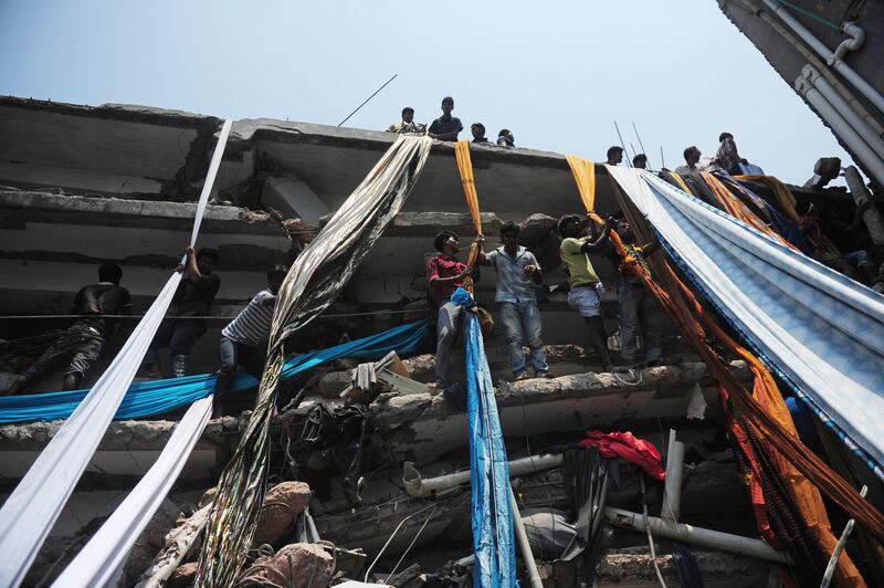 Bangladeshi garment workers use lengths of textile to evacuate from the rubble after an eight-storey building collapsed in Savar, on the outskirts of Dhaka, on April 24, 2013. At least 15 people were killed and many more feared dead when an eight-storey building housing a market and garment factory collapsed in Bangladesh on Wednesday, officials said.  AFP PHOTO/Munir uz ZAMAN
 *** Local Caption ***  978781-01-08.jpg