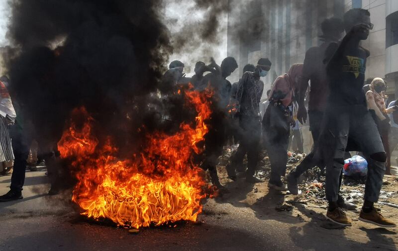 Protesters walk past burning tyres in the capital Khartoum. AFP