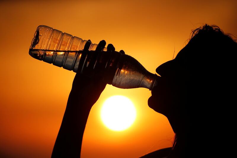 A woman drinks water during sunset, as a heatwave hits France, in Cagnicourt near Cambrai, France. Reuters