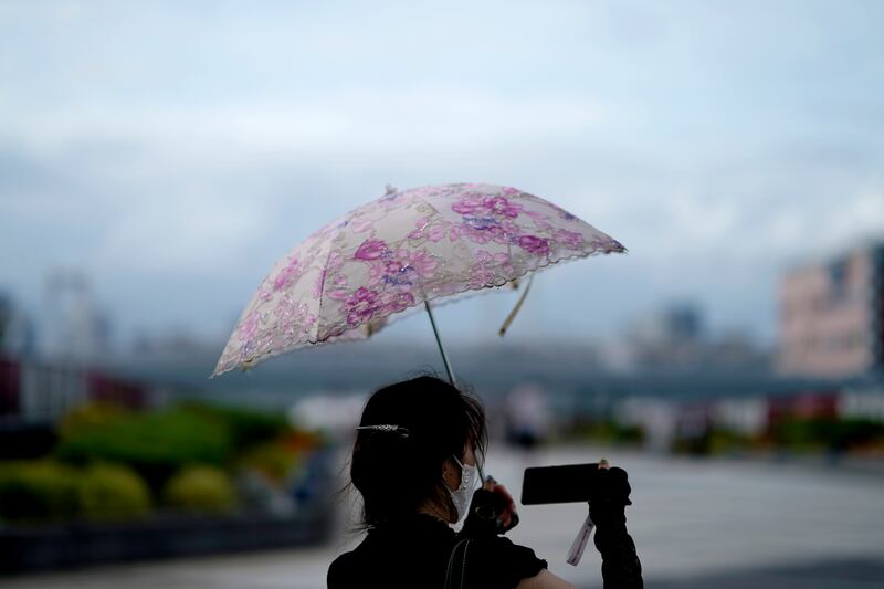 A woman takes a photo of the Tokyo skyline. Japan recently earned the dubious distinction of being one of only two advanced economies to have its growth outlook cut by the International Monetary Fund. Photo: AP