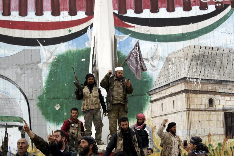Rebel fighters, one of them carrying a flag used by Al Qaeda’s Nusra Front, celebrate at the Mihrab roundabout in the Idlib city centre on March 28, 2015. Khalil Ashawi / Reuters