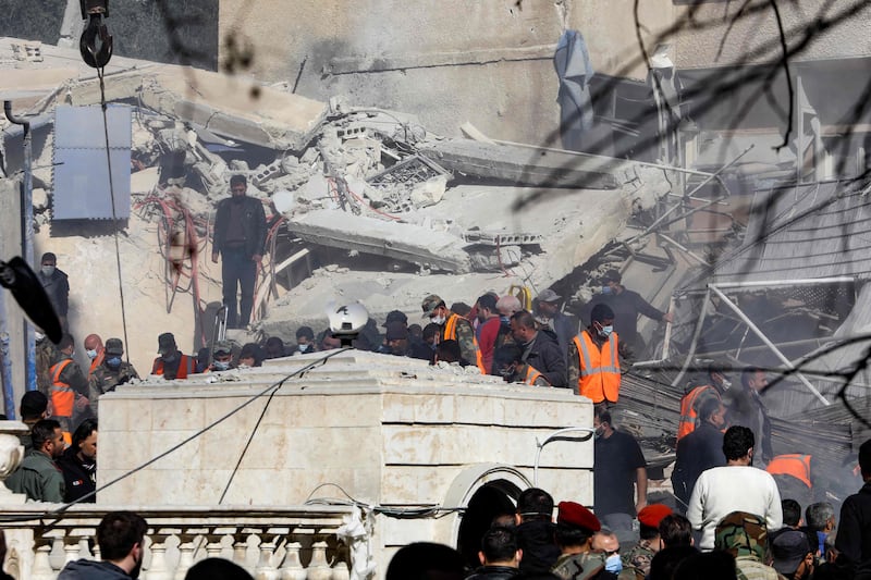 People and rescuers gather in front of a building destroyed in an Israeli strike in Damascus on January 20. AFP