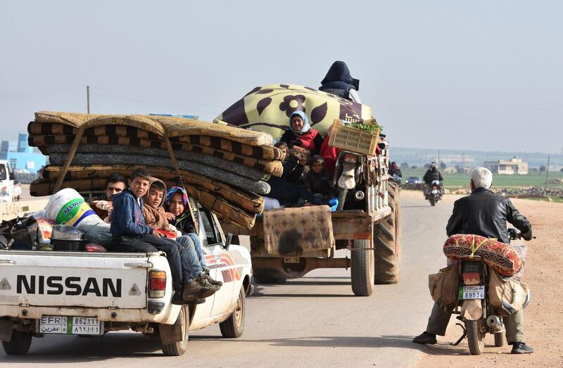 Civilians fleeing the city of Afrin in northern Syria are seen on the back of a pick up truck as they enter the town of Tal Rifaat in the government-controlled part of the northern Aleppo province, on March 18, 2018. George Ourfalian / AFP
