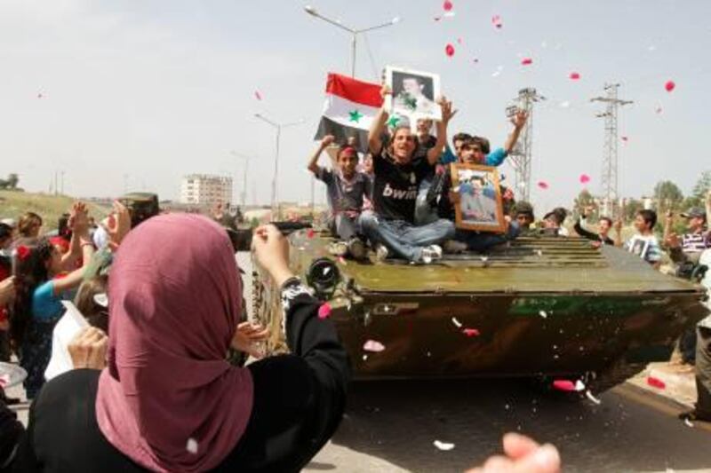 EDITOR'S NOTE: THIS PICTURE WAS TAKEN ON A GUIDED GOVERNMENT TOUR
Syrian women shower army troops with rose petals and rice as youths holding up portraits of President Bashar al-Assad ride on an army tank pulling out of the southern protest hub of Daraa on May 5, 2011 after a military lockdown of more than a week during which dozens of people were killed in what activists termed as "indiscriminate" shelling of the town, some 100 kms south of the capital Damascus. The Syrian military's political department chief insisted that troops "did not confront the protesters" in Daraa, adding that 25 soldiers were killed and 177 wounded during the military campaign to "search for terrorists". AFP PHOTO/LOUAI BESHARA
 *** Local Caption ***  929705-01-08.jpg
