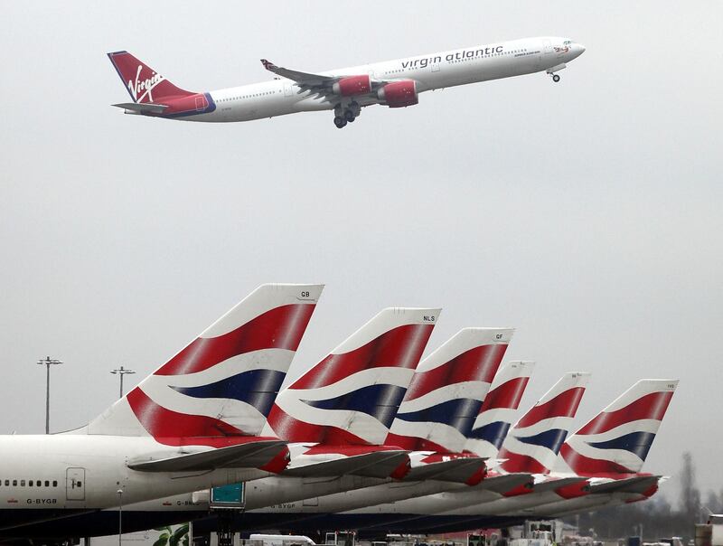 A Virgin Atlantic airplane takes off over British Airways jets sitting at Terminal 5 at Heathrow airport in London, U.K., on Friday, March 19, 2010. British Airways Plc Chief Executive Officer Willie Walsh will hold talks with the Unite union for a second day as he seeks to head off a three-day strike by 12,000 cabin crew thatÕs scheduled to begin tomorrow. Photographer: Simon Dawson/Bloomberg

