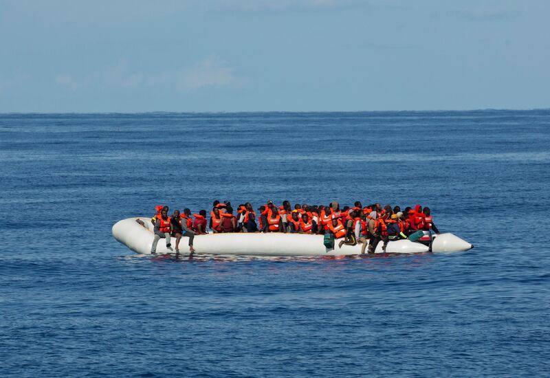In this photo taken on Saturday, Oct. 26, 2019, migrants stand on a dinghy boat off the coast of Libya. A humanitarian aid group said gunmen on Libya-flagged speedboats threatened the crew of its rescue ship Alan Kurdi and the migrants it was rescuing Saturday, firing shots into the air and water. Sea-Eye's spokesman Gorden Isler told The Associated Press that the unprecedented incident on the Mediterranean Sea was a "total shock" for the rescue crew, but that they managed to bring all the roughly 90 migrants on board. (Sea-Eye via AP)