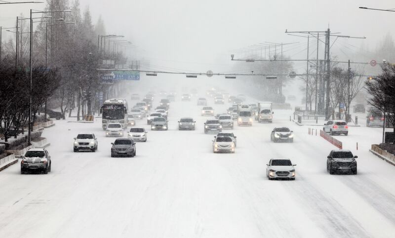 Heavy snowfall slows traffic to a crawl in Gwangju, South Korea. EPA

