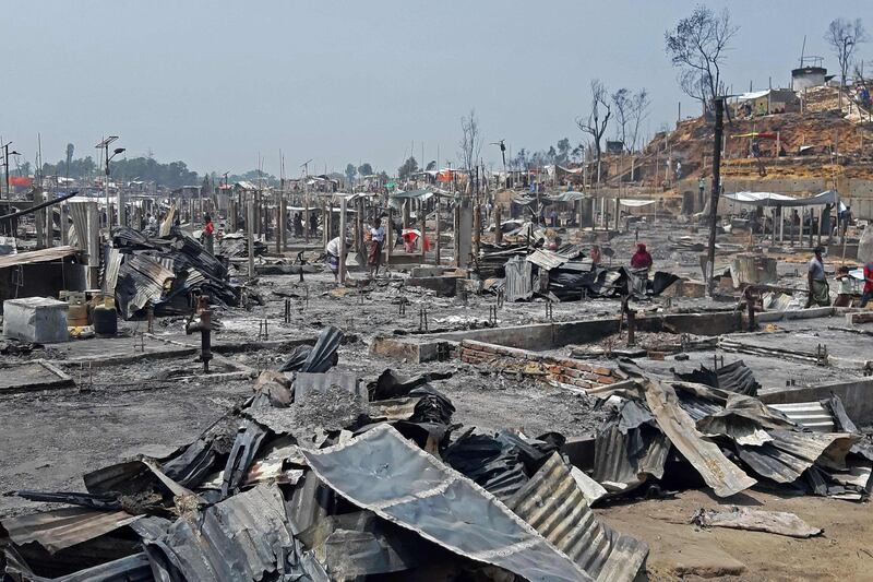 People are seen amidst the debris at a Rohingya refugee camp in Ukhia after a huge blaze forced around 50,000 people to flee. AFP