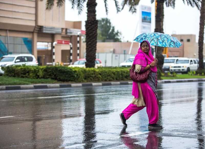 A woman crosses the street during a morning downpour in Dubai on Saturday. Victor Besa for The National