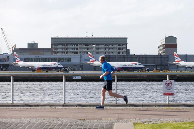 LONDON, ENGLAND - MARCH 29: A jogger passes grounded aeroplanes at London City Airport on March 29, 2020 in London, England. The field hospital will initially contain 500 beds with ventilators and oxygen and will have the capacity to eventually hold up to 4,000 COVID-19 patients. (Photo by Hollie Adams/Getty Images)