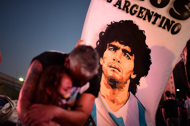 A father and daughter mourn as they gather by the Buenos Aires Obelisk to pay homage to Maradona. AFP