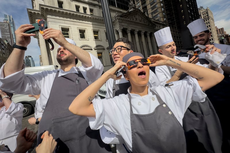 Restaurant workers in Manhattan take a break to view the solar eclipse in New York City. AP