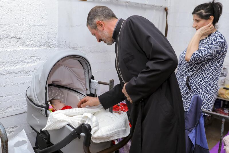 In this handout photo released by Armenian Foreign Ministry, an Armenian church priest looks a a baby in a bombshelter to protect against shelling in Stepanakert, the self-proclaimed Republic of Nagorno-Karabakh, Azerbaijan.  AP