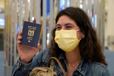 FILE - In this Nov. 26, 2020 file photo, an Israeli passenger from a flyDubai flight from Tel Aviv, Israel, waves her Israeli passport on arrival at Dubai International Airport's Terminal 3 in Dubai, United Arab Emirates. Israel's National Security Agency on Monday, March 29, 2021 advised tourists against travel to the United Arab Emirates and other countries across the region, citing the threat of attack by arch-enemy Iran. (AP Photo/Jon Gambrell, File)