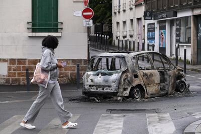 A person walks near the remains of a burnt out car following a night of looting and rioting in Montreuil, near Paris, July 1, 2023. EPA / Julien Mattia