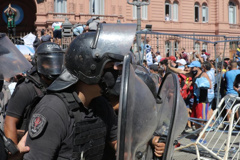 Police officers try to contain the crowd as fans tried to climb over the fence to enter Casa Rosada during Diego Maradona's funeral. Getty