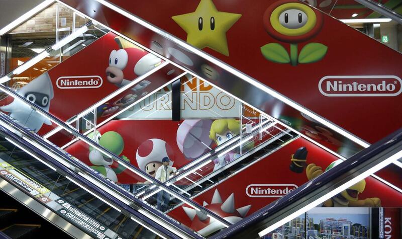 A man rides an escalator past Nintendo advertisements at an electronics retail store in Tokyo. Japan’s Nintendo expects to return to profit in the current business year after three straight years of losses, helped by a series of new video games for its Wii U console. Toru Hanai / Reuters