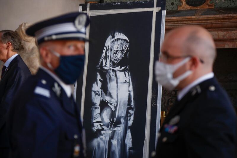 A recovered stolen artwork by British artist Banksy, depicting a young female figure with a mournful expression, that was painted as a tribute to the victims of the 2015 terrorist attacks at the Bataclan music hall in Paris, is shown during a ceremony at the French embassy in Rome. AP Photo