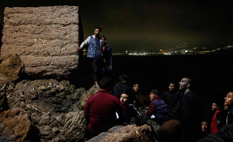 Moroccan migrants climb up a rocky cliffside in the northern town of Fnideq as they attempt to cross the border from Morocco to Ceuta. AFP