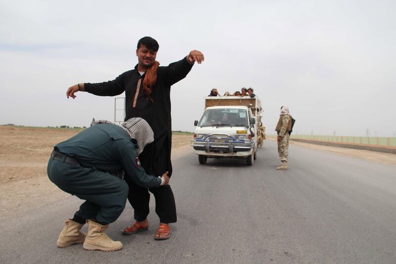 Afghan security officials pat down vistors at a roadside checkpoint in Helmand, Afghanistan, April 15. EPA