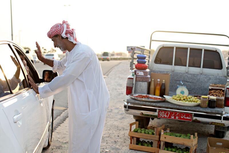 August 15 2011 - Shahama, UAE - Mohammad Ali Saeed Al-Mazrooi greets a passer-by along a roundabout in Old Shahama prior to Iftar. Mohammad is originally from Oman but has lived in the UAE for 40 years. He has spent the last 4 living in Shahama and loves living in the Emirates even though his family are still in Oman. He sells limes, lemons, dates and honey that are all from Sohar, Oman. (Razan Alzayani / The National) 