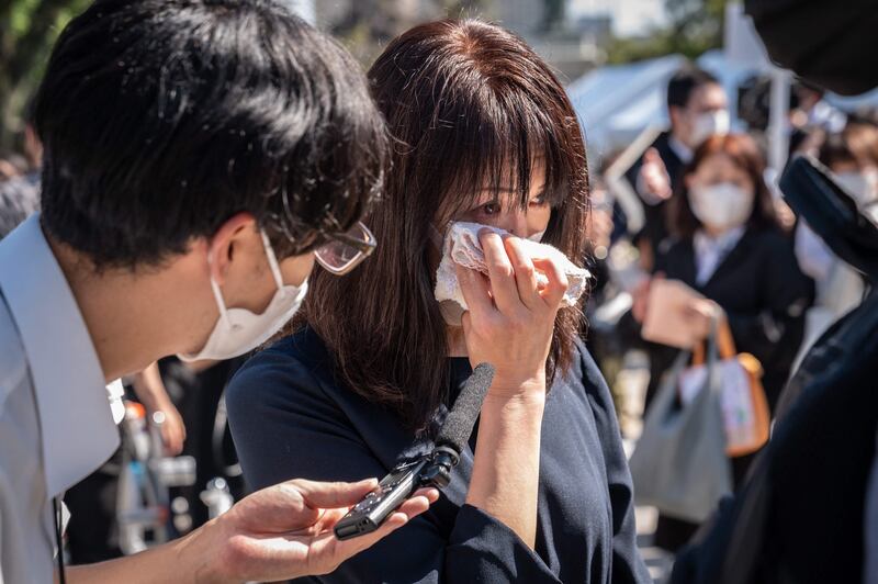 A woman cries during an interview after leaving flowers. AFP