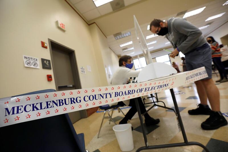 A poll worker assists a voter on the last day of early in-person voting for the general elections near tape identifying the Mecklenburg County Board of Elections in Cornelius, North Carolina.  Reuters
