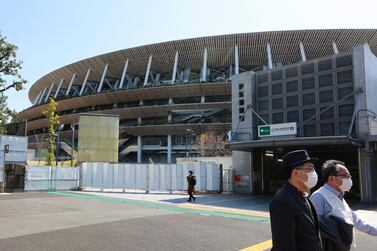 People walk past at the National Stadium in Tokyo on March 10, 2021. AP