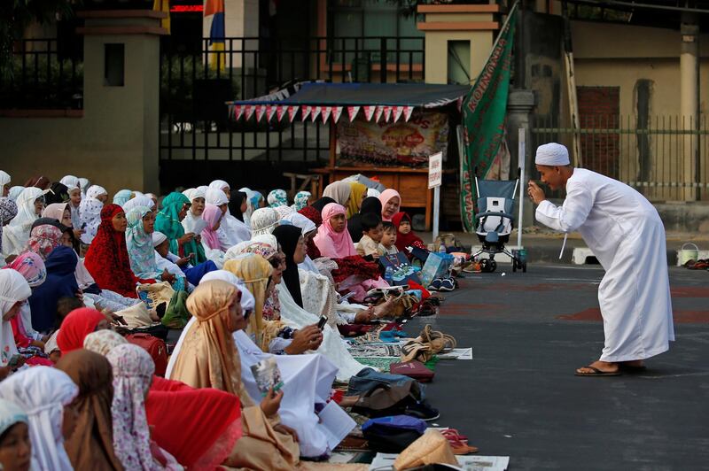 An Indonesian man takes pictures as he attends Eid Al Adha prayers on a street in Jakarta, Indonesia. Reuters