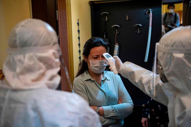 A health officer wearing protective clothing checks the temperature of a resident, believed to have been in contact with coronavirus patients. AFP