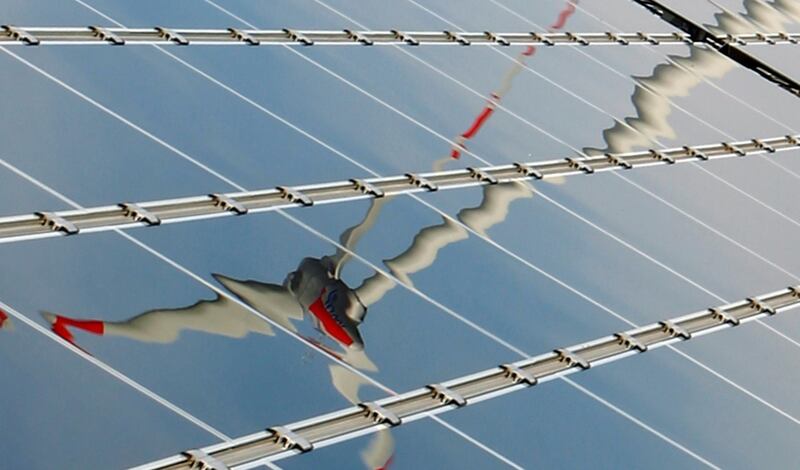 FILE PHOTO: A power generating wind turbine is reflected in solar panels, March 10, 2010. REUTERS/Thomas Bohlen/File Photo