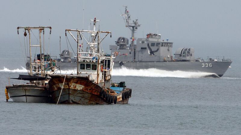 FILE- In this May 29, 2009, file photo, a South Korean navy vessel passes by fishing boats near Yeonpyong Island, off the northwest coast of South Korea, May 29, 2009. South Korea's military on Friday, Sept. 27, 2019, says it fired warning shots toward a North Korean boat crossing their sea border, then it sent a navy mechanic to repair the drifting boat's engine so it could return to the North. (Ahn Jong-won/Yonhap via AP)