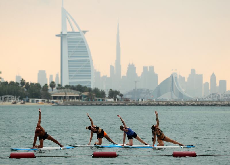 People take part in oga on paddle boards at Ignite Water Sports on the Palm in Dubai on July 17.